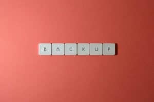 Free Close-up of keyboard keys spelling 'BACKUP' placed on a coral-colored surface. Stock Photo